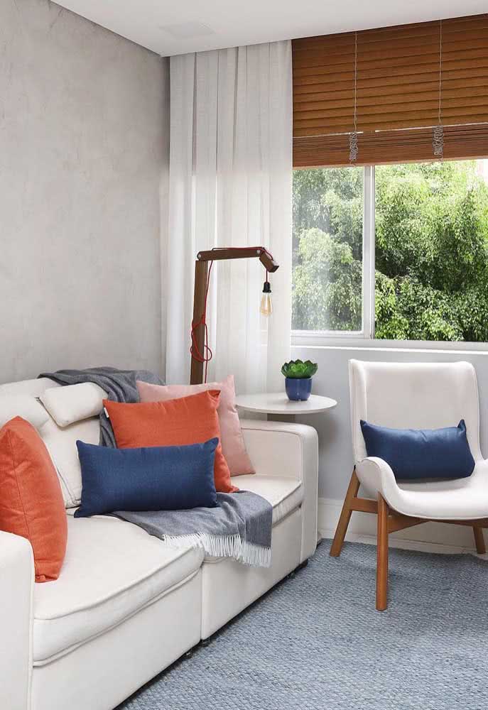 Sala de estar de apartamento com sofá branco e almofadas coloridas.