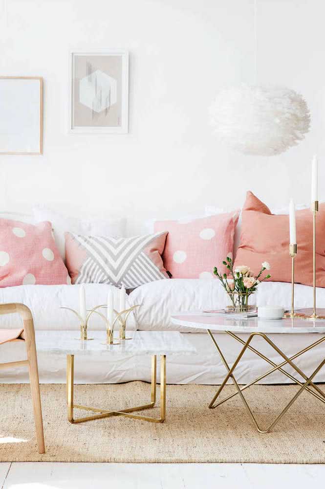 Sofá aconchegante de tecido com almofadas na cor rosa.