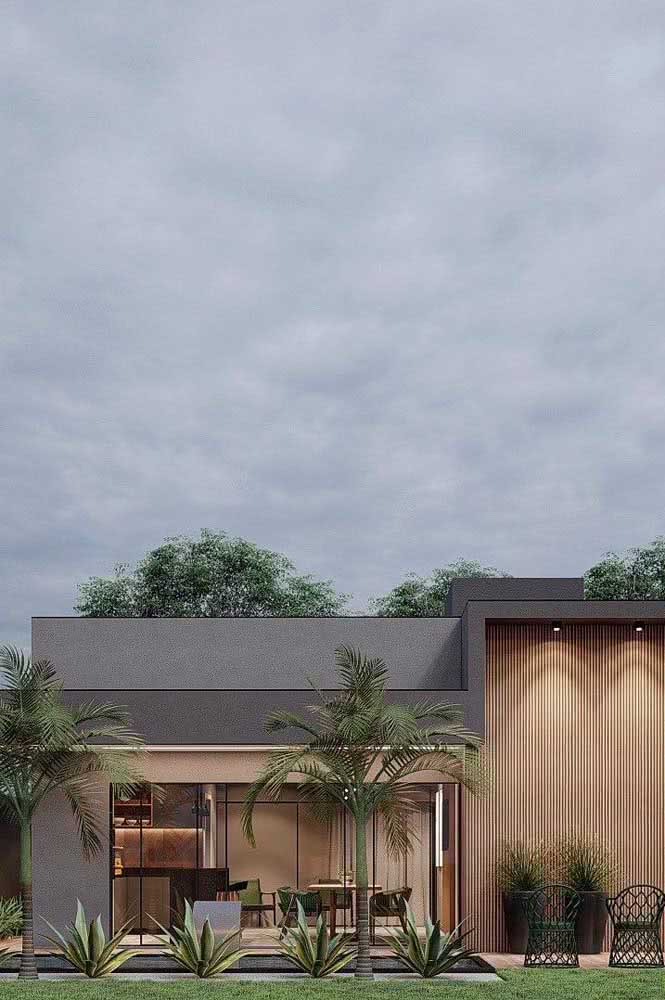 Fachada de casa térrea moderna com revestimento de madeira, paisagismo e projeto de iluminação.