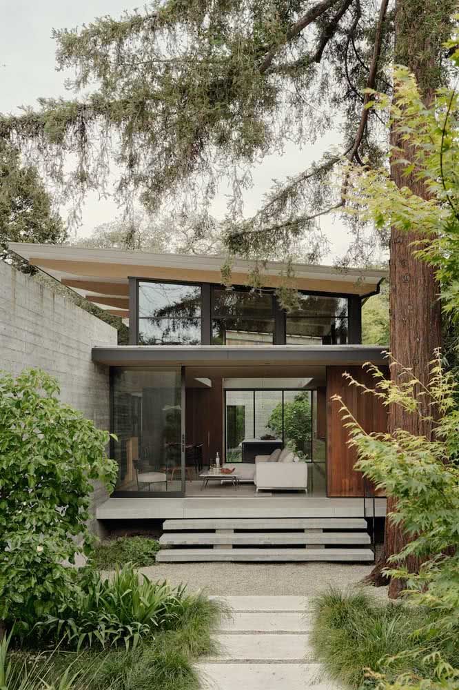 Casa térrea moderna, integrada as áreas verdes do terreno e com pé-direito alto.