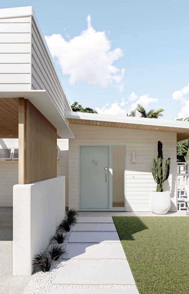 Casa branca e térrea de madeira com garagem coberta e jardim com gramado.