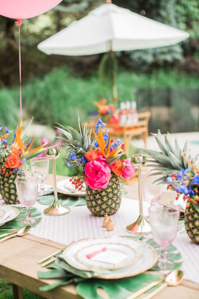 Detalhe da mesa em área externa com um belíssimo arranjo montado em abacaxi.
