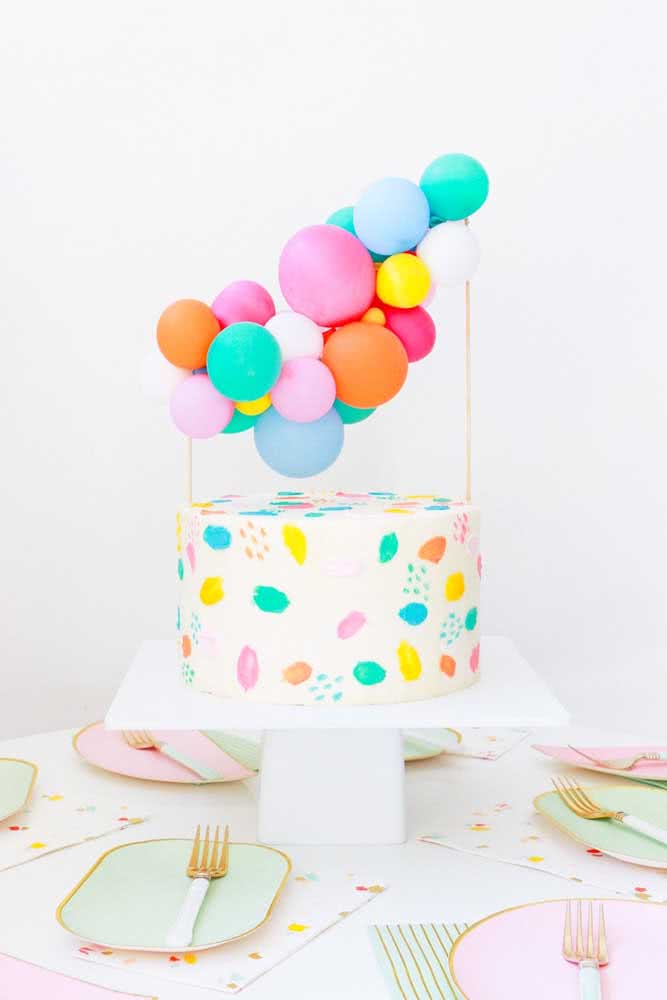 Topper de bolo colorido feito com balões. Repare que o enfeite combina com a decoração do bolo