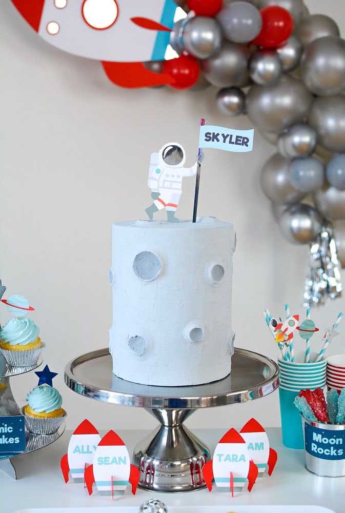 Topper de bolo infantil com tema astronauta. O enfeite simples em papel complementa a decoração da festa
