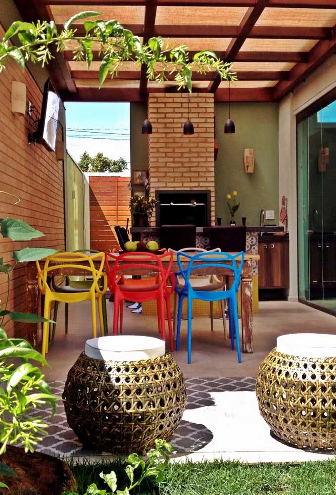 Área de churrasco rústica no quintal com destaque para as charmosas cadeiras coloridas
