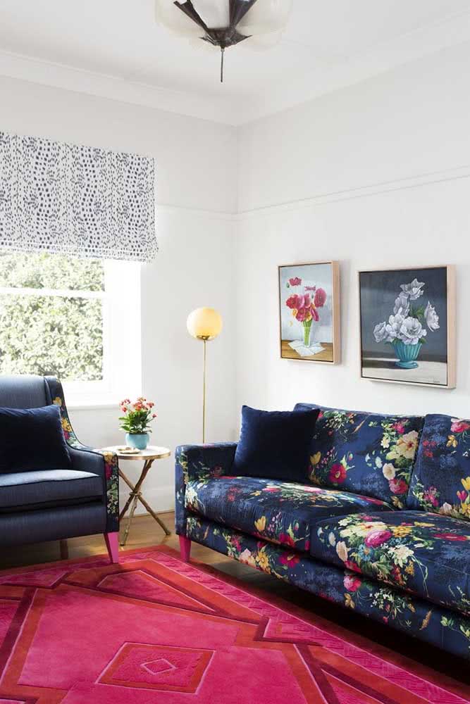Sofá estampado floral combinando com o tapete rosa e as demais referências florais espalhadas pela sala