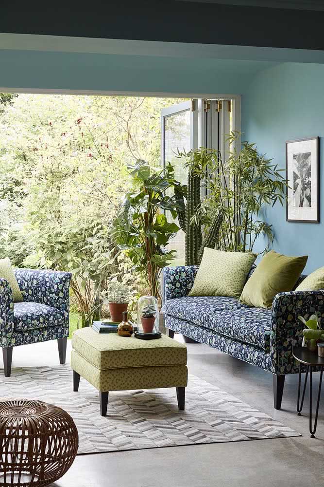 Decoração de sala com sofá estampado azul. A mesa de centro e o tapete também trazem estampas, só que mais discretas