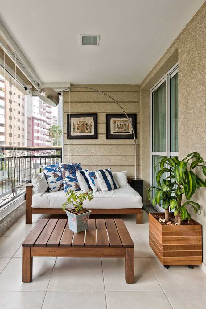 Sofá, mesa, plantas e quadros compõe a decoração dessa varanda charmosa de apartamento