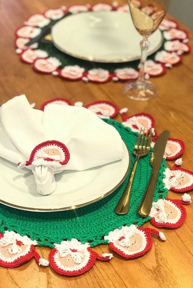 Sousplat de crochê de natal decorado com papai noel e as cores típicas dessa época do ano. Repare que o anel do guardanapo traz o mesmo tema
