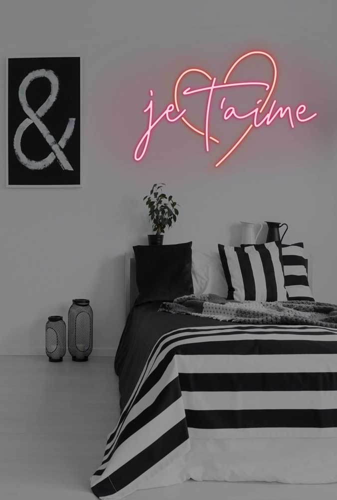O quarto em preto e branco aceitou muito bem o letreiro neon vermelho