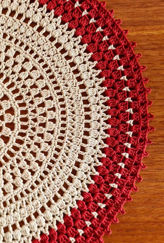 Aqui, o bico de crochê para tapete redondo se destaca ao trazer o vermelho em contraste com o tom cru do barbante