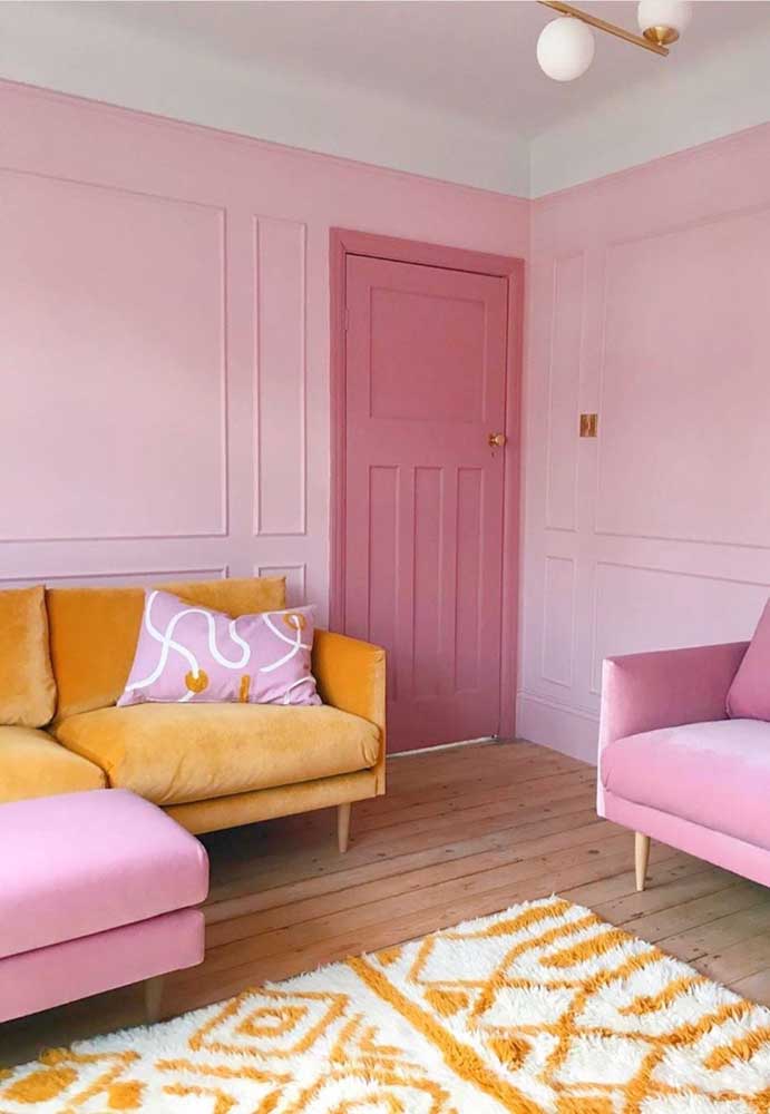 Sala com sofá rosa, parede rosa e até uma porta rosa!