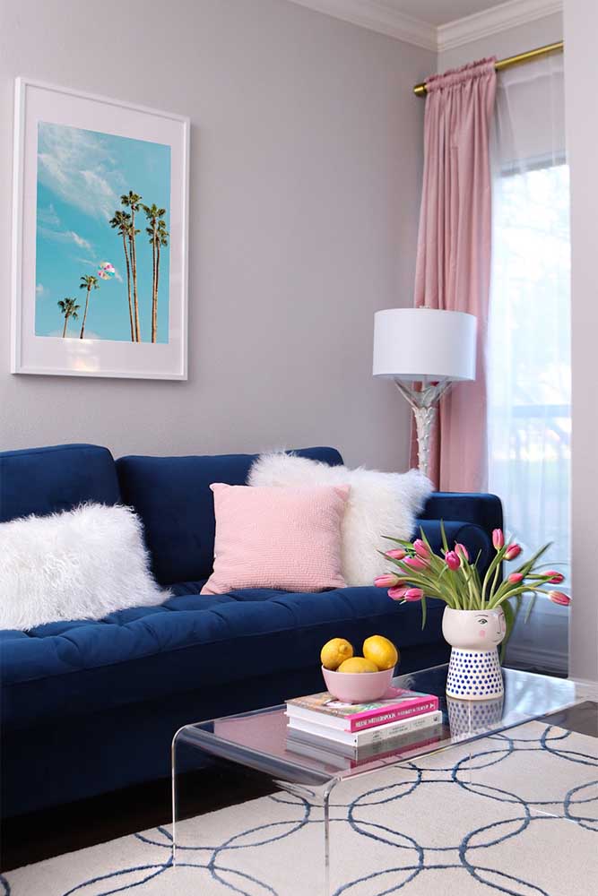 Já aqui, a dica é combinar o sofá azul marinho com detalhes cor de rosa