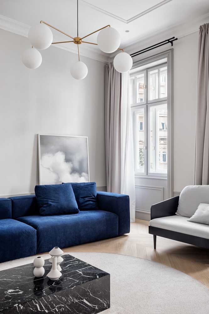 Decoração com sofá azul marinho em contraste com o fundo acinzentado