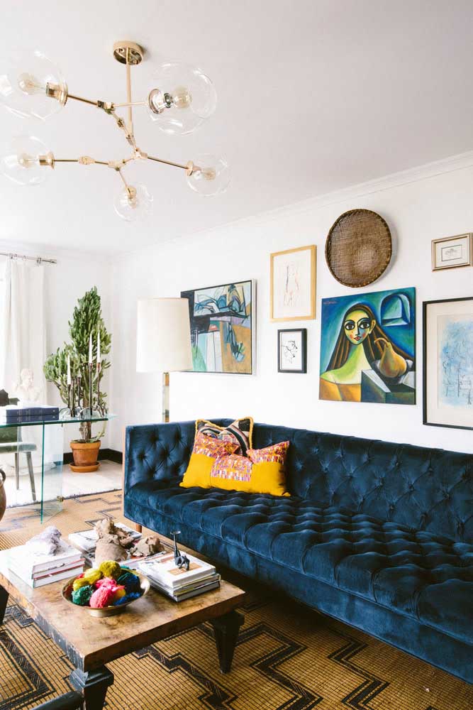 A sala ampla e alongada traz um sofá azul marinho no mesmo formato