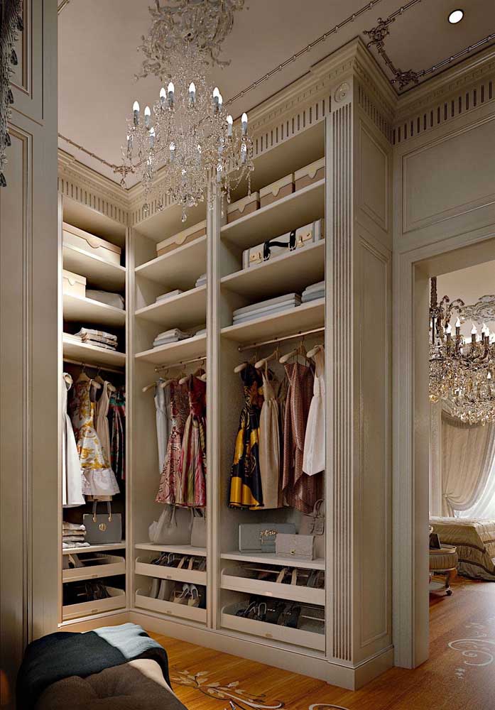 Closet luxuoso clássico com pé direito alto, colunas e um lustre de cristal para fechar o conjunto