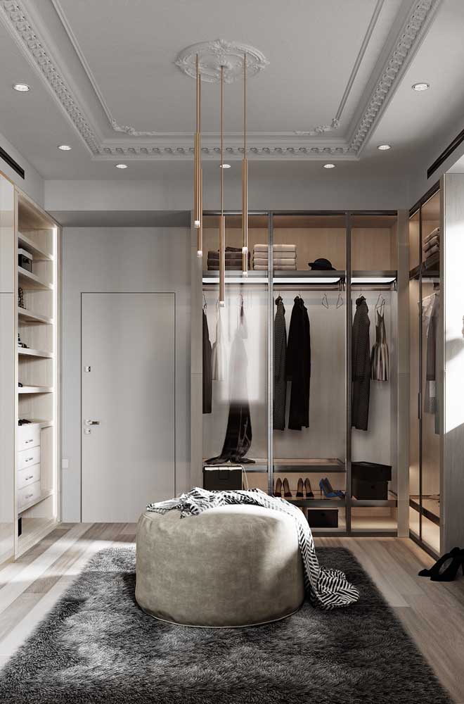 Closet luxuoso com pufe e tapete para deixar o espaço mais confortável e aconchegante