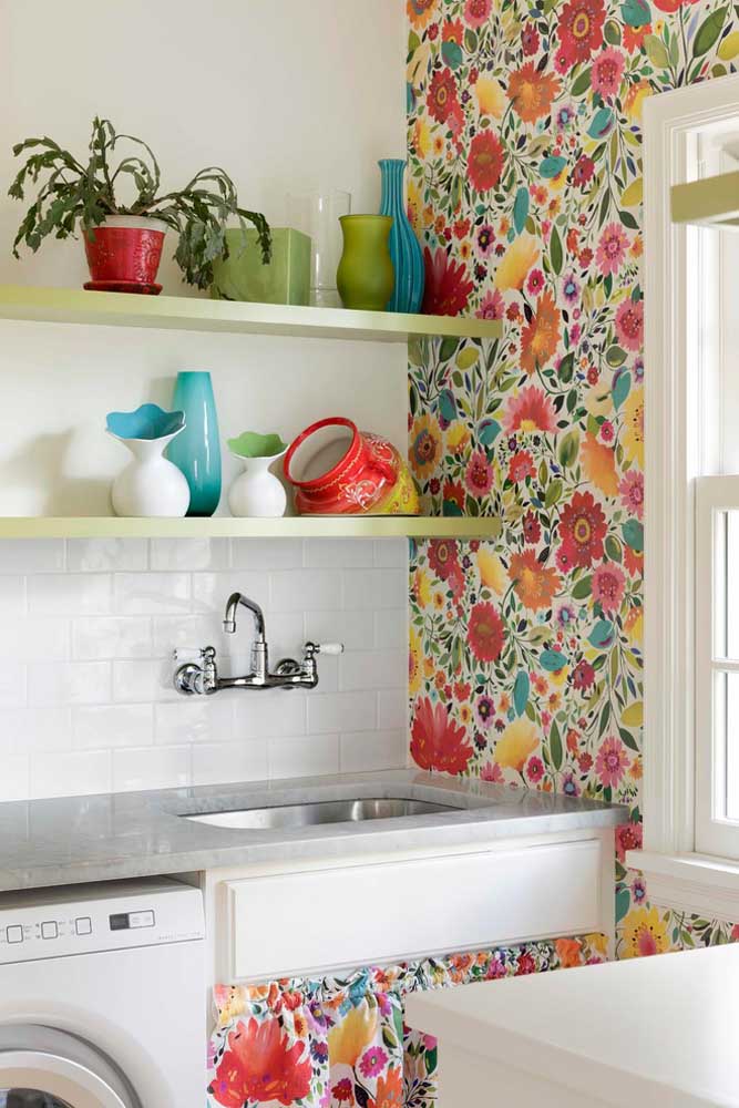 Aqui, o tecido chita florido estampa a parede da cozinha de móveis brancos