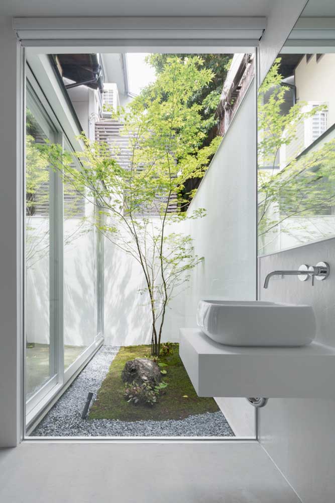 O verde do jardim de inverno faz um lindo contraste com o banheiro branco