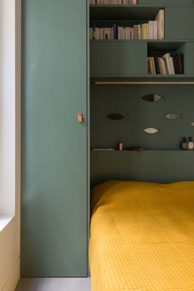 Armário verde planejado com nichos para livros e objetos decorativos.
