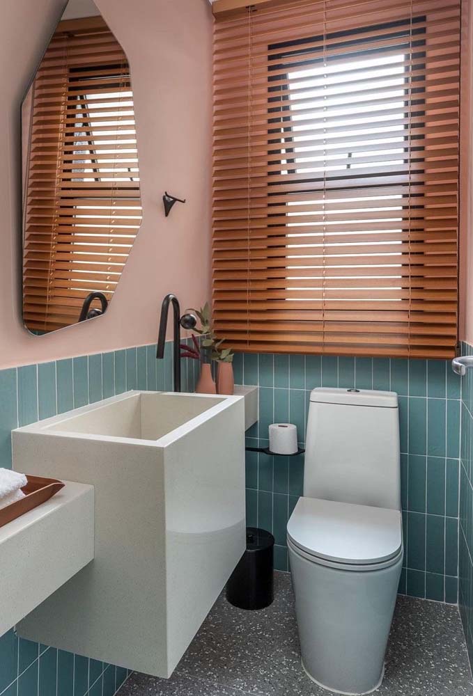 Banheiro pequeno com pintura rosa combina perfeitamente com a persiana horizontal de madeira.