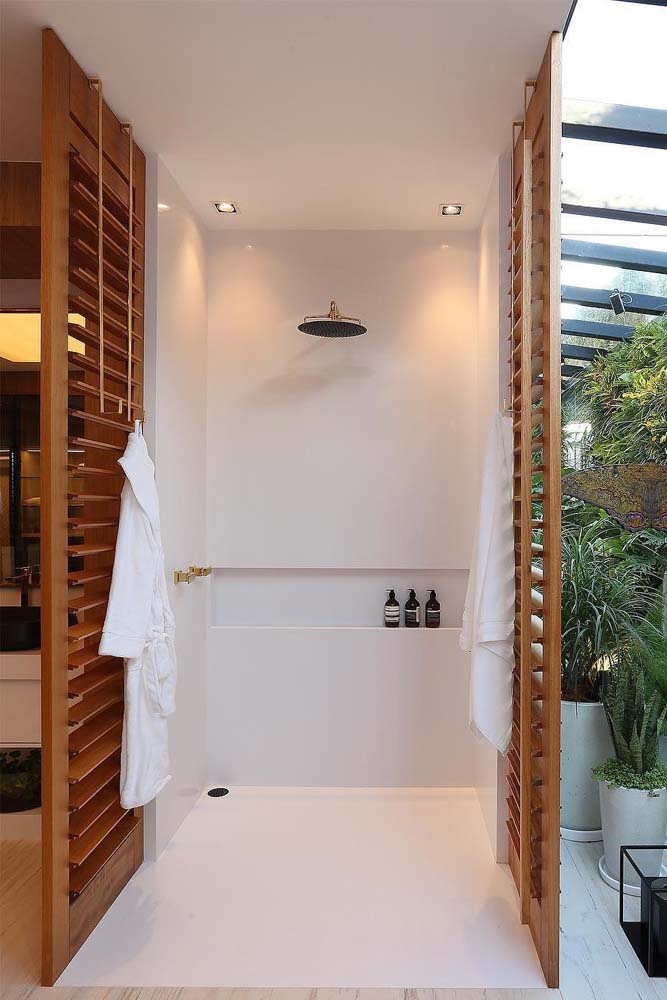Já neste banheiro de quarto de casal, a persiana de madeira foi utilizada para dar privacidade a área de banho, quando necessário.