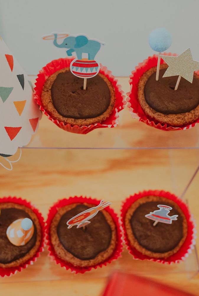 Cupcakes com palitinhos e ilustrações para decorar a mesa da festa.
