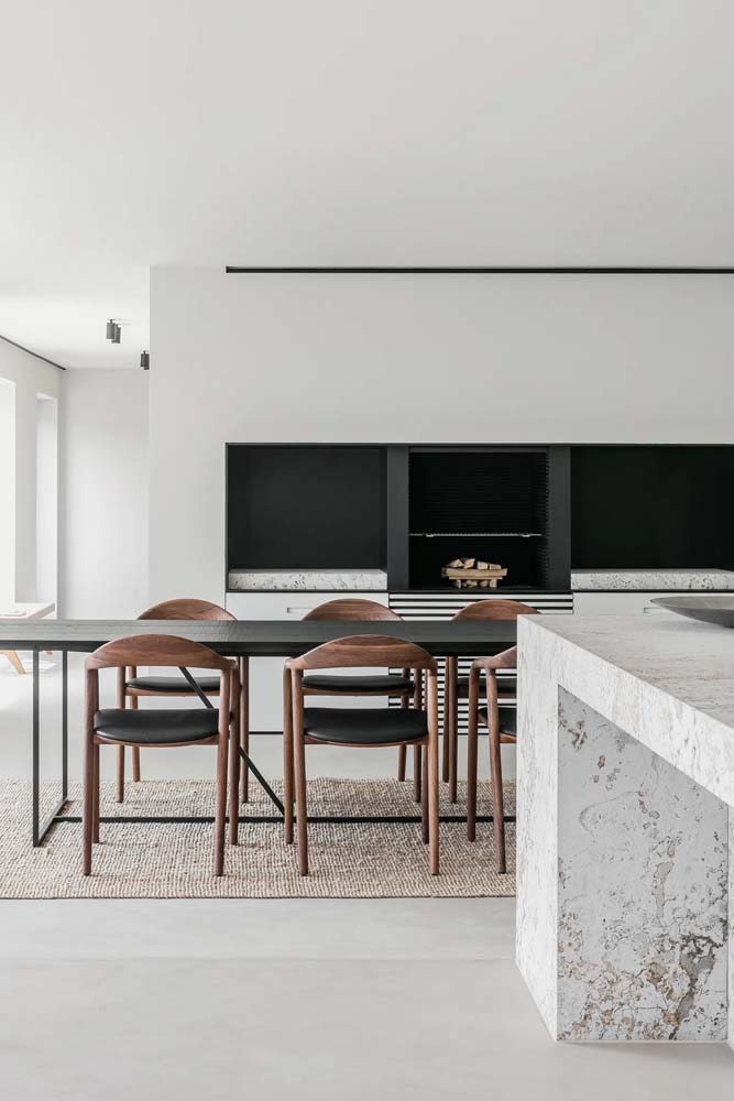 Decoração de sala integrada minimalista com mesa de madeira preta e lareira.