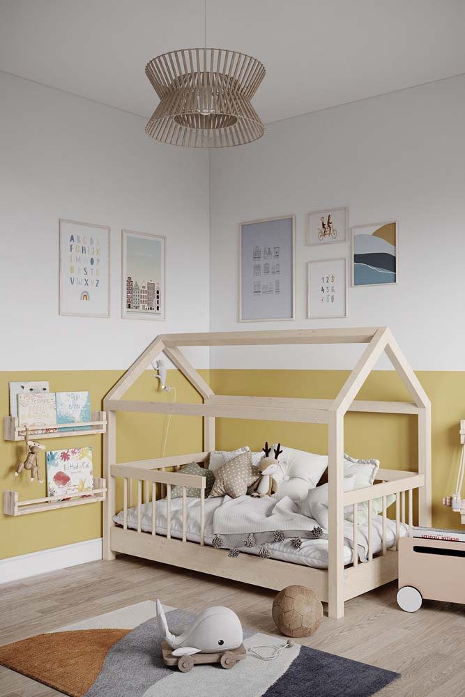 Quarto de bebê simples e cheio de charme com pintura amarela clara em meia parede e móveis de madeira clara.