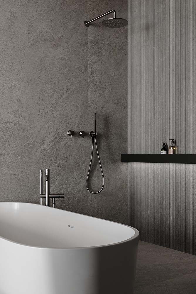 Banheiro com banheira todo cinza, metais modernos e luxuosos.
