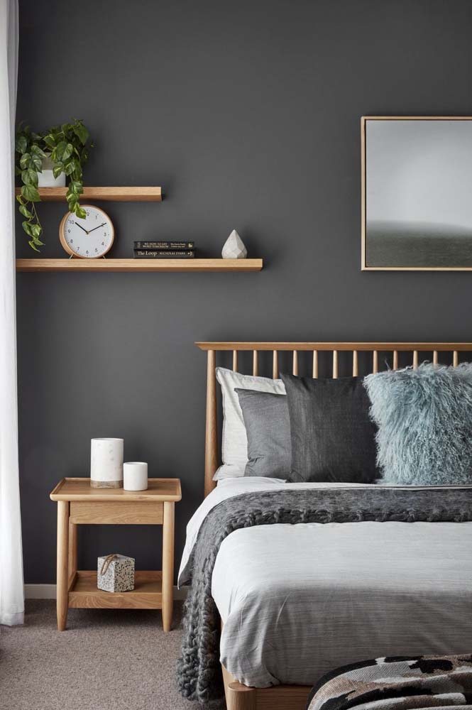 Decoração minimalista com pintura cinza no quarto de casal e cama de madeira.