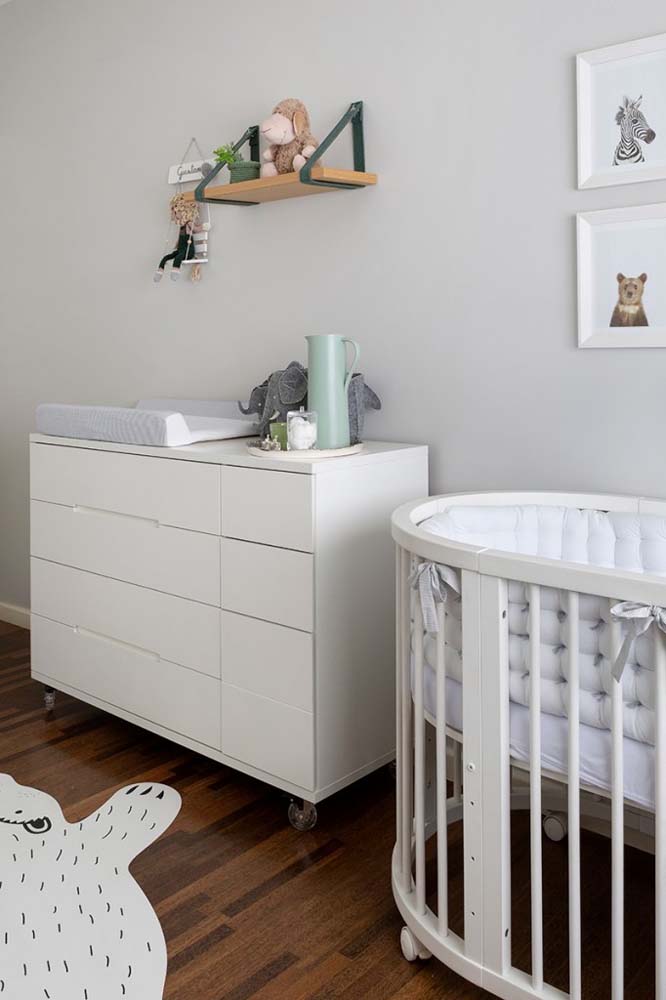 Cinza claro na pintura da parede e móveis de madeira na cor branca: uma clássica combinação para quartos de bebê.