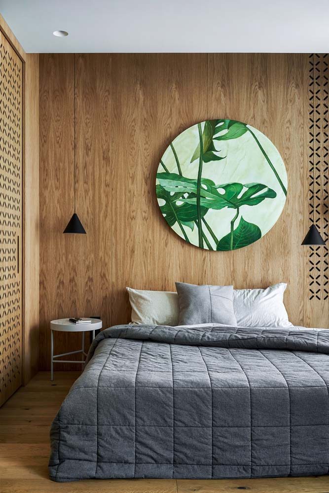 Decoração de quarto de casal moderna com ampla presença da madeira, no piso e no armário. Quadro de ilustração de plantas se destaca no ambiente.