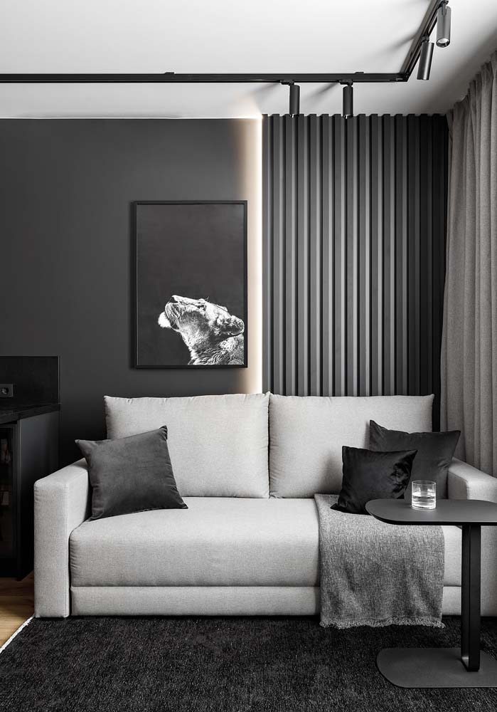 Sala com tons escuros recebe quadro com fotografia também preto e branca.