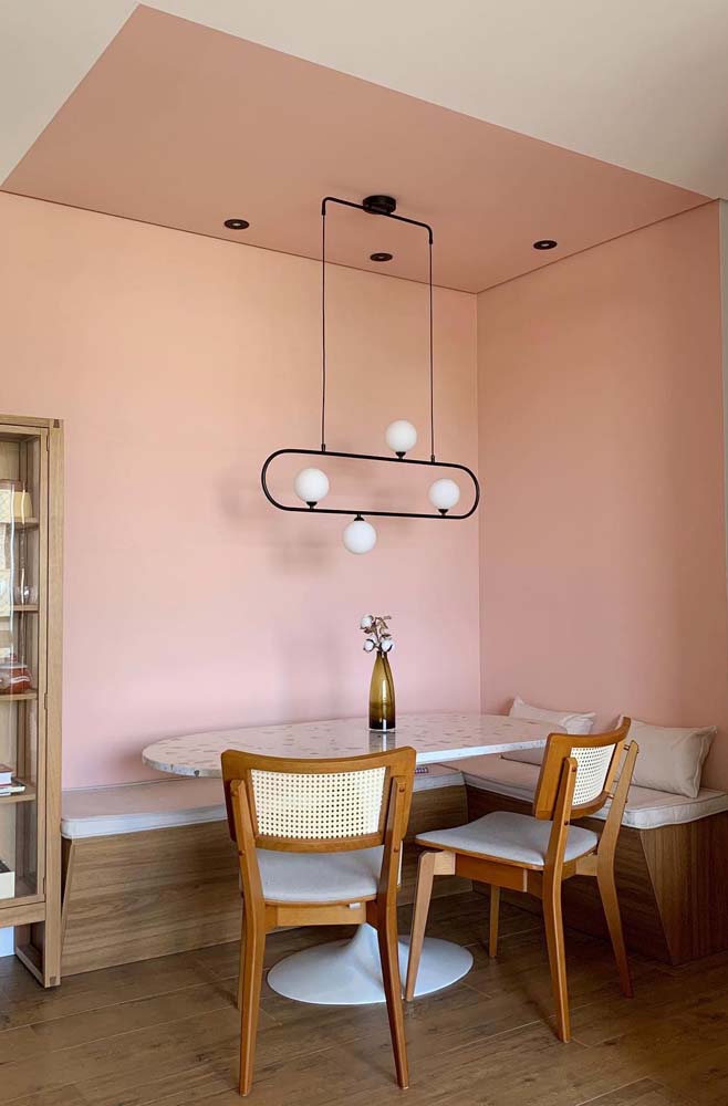 A pintura rosa nas paredes e no teto ajudam a delimitam o ambiente de jantar desse canto alemão com mesa Saarinen oval. 