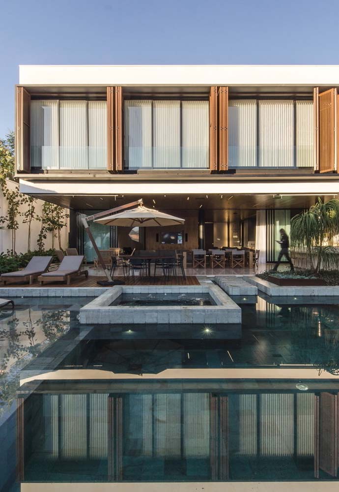 Área gourmet com piscina moderna seguindo o mesmo estilo da fachada da casa