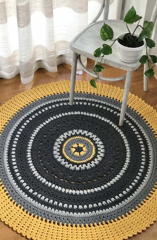 Para uma sala moderna aposte em um tapete de crochê redondo amarelo, preto e cinza