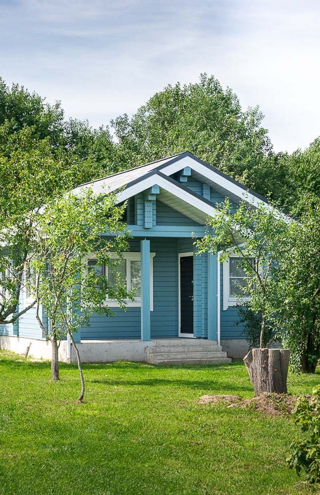 Casa pequena e simples de madeira com pintura azul clara. A pintura é um recurso acessível para mudar a aparência do material.