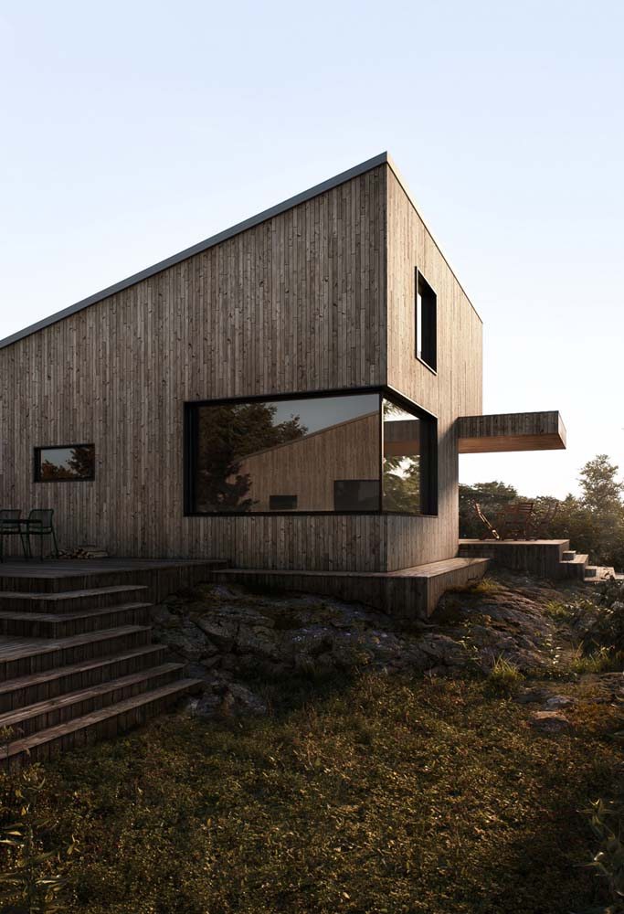 Modelo de casa de madeira super moderna com telhado inclinado em uma água e janelas de vidro.