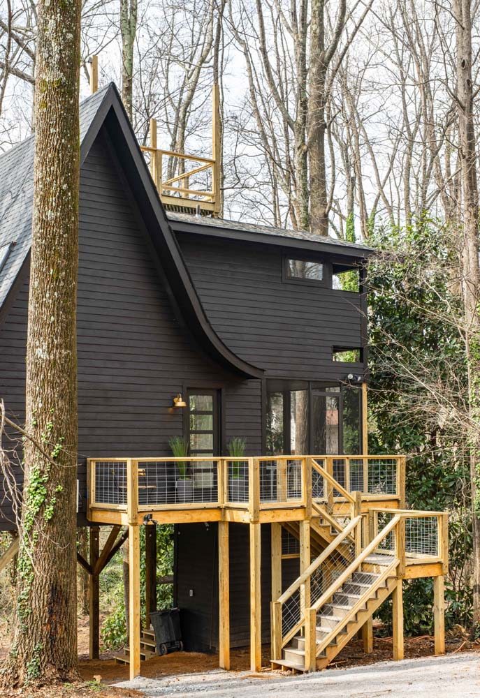 Modelo de casa de campo moderna com madeira e telhas na cor preta.