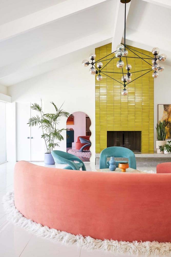 Uma sala de estar diferente e colorida com espelho decorativo com curvas na lateral.