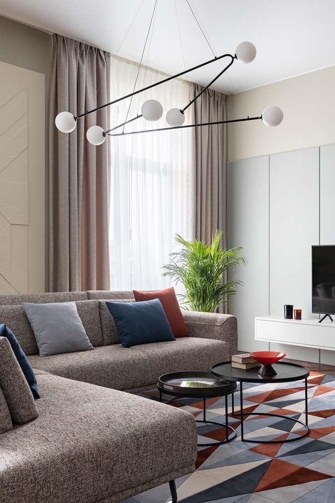 Sala moderna com sofá de canto com tecido cinza e almofadinhas coloridas para completar.