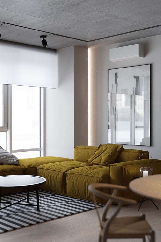 Sala clean com ampla presença do branco onde o sofá se destaca com tecido mostarda.