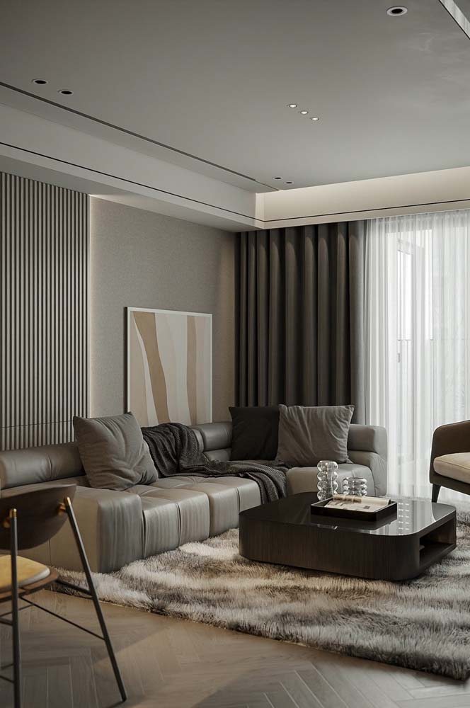 Ambiente da sala de estar com cores neutras e sofá de canto cinza com tecido de couro.