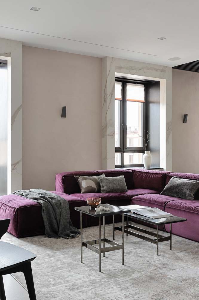 Modelo de sofá lilás em L para uma sala com cores claras.