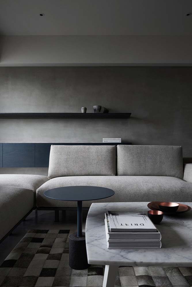 Sala minimalista com sofá de tecido cinza de canto.