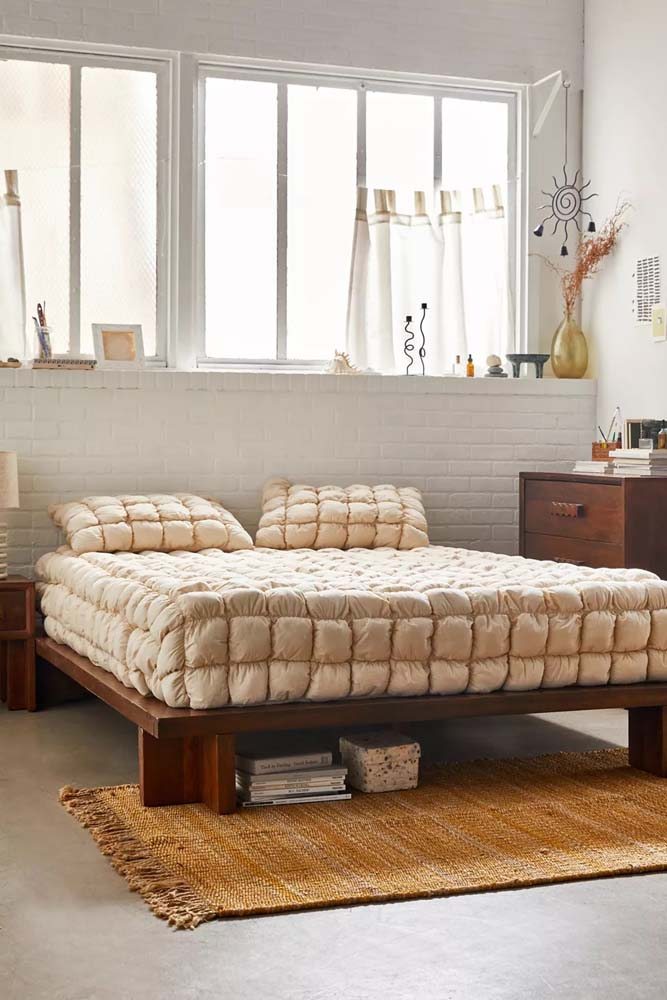 Decoração minimalista com cama baixa de madeira simples na mesma tonalidade da mesa de cabeceira e da cômoda.