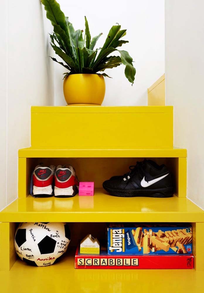 Escada compacta com madeira revestida com pintura amarela e nichos para armazenar pequenos objetos.