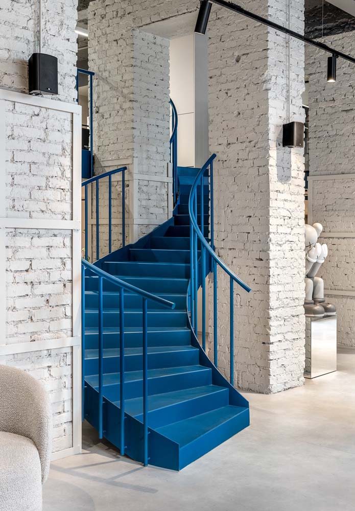 Escada metálica com pintura azul em formato curvo para espaço comercial.