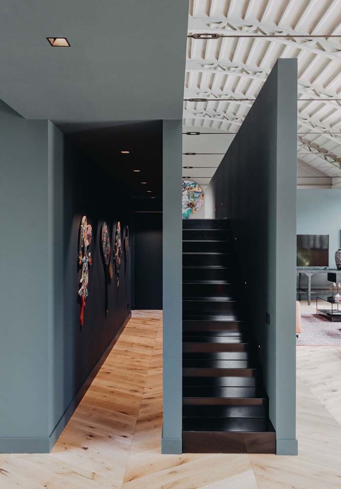 Ideia de escada de madeira escura simples cercada por paredes de alvenaria.